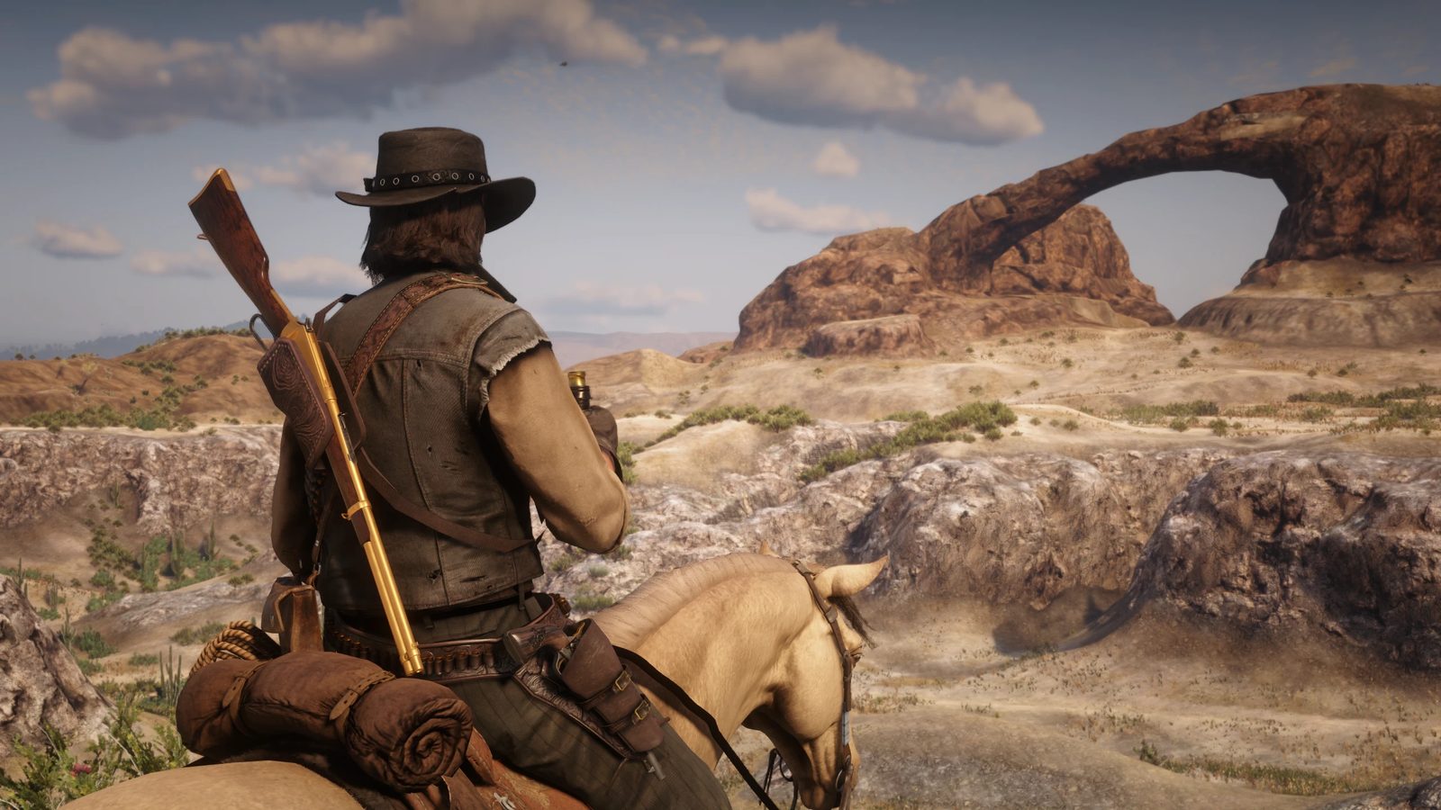 A rider facing a stone arch in the desert of Nuevo Paraíso, in the RDR2 mod